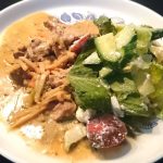 En tallrik med asiatisk köttgryta och en grönsallad med tomater och dressing.