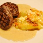 Grillad oxfilé serverad med rotfruktsgratäng och sås på en tallrik.