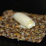 En bit fröknäcke med en rullad smörbit på toppen.