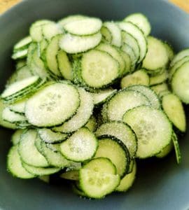 En skål med skivade gurkor som är strödda med socker.