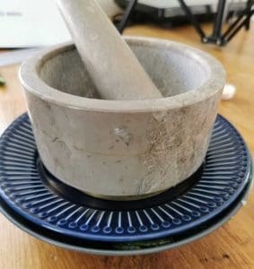 Grå mortel med stöt placerad på en blå och svart underlägg.