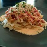 En tallrik med LCHF carbonara som innehåller pasta, grädde och bacon, garnerad med parmesan och persilja.