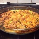 En gratäng med köttfärs och grönsaker i en glasform på en spis.