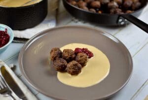 En tallrik med köttbullar serverade med sås och lingonsylt.