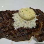 Grillad biff med en klick smör på toppen, serverad på en vit tallrik.