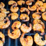 Grillade scampi som ligger på ett grillgaller med tydliga grillmärken.