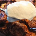 En sked med creme toum framför grillat kött i en skål.