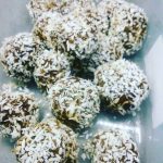 Kokosbollar täckta med riven kokos i en transparent behållare.