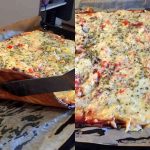 En LCHF pizza med ost, grönsaker och örter på en plåt med bakpapper.
