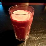 Ett glas med bärsmoothie som har en krämig konsistens och en ljusare yta.