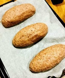 Tre köttfärslimpor placerade på ett bakplåtspapper på en plåt.