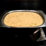 En metallskål med varm örtsås, innehållande en krämig blandning med örter.