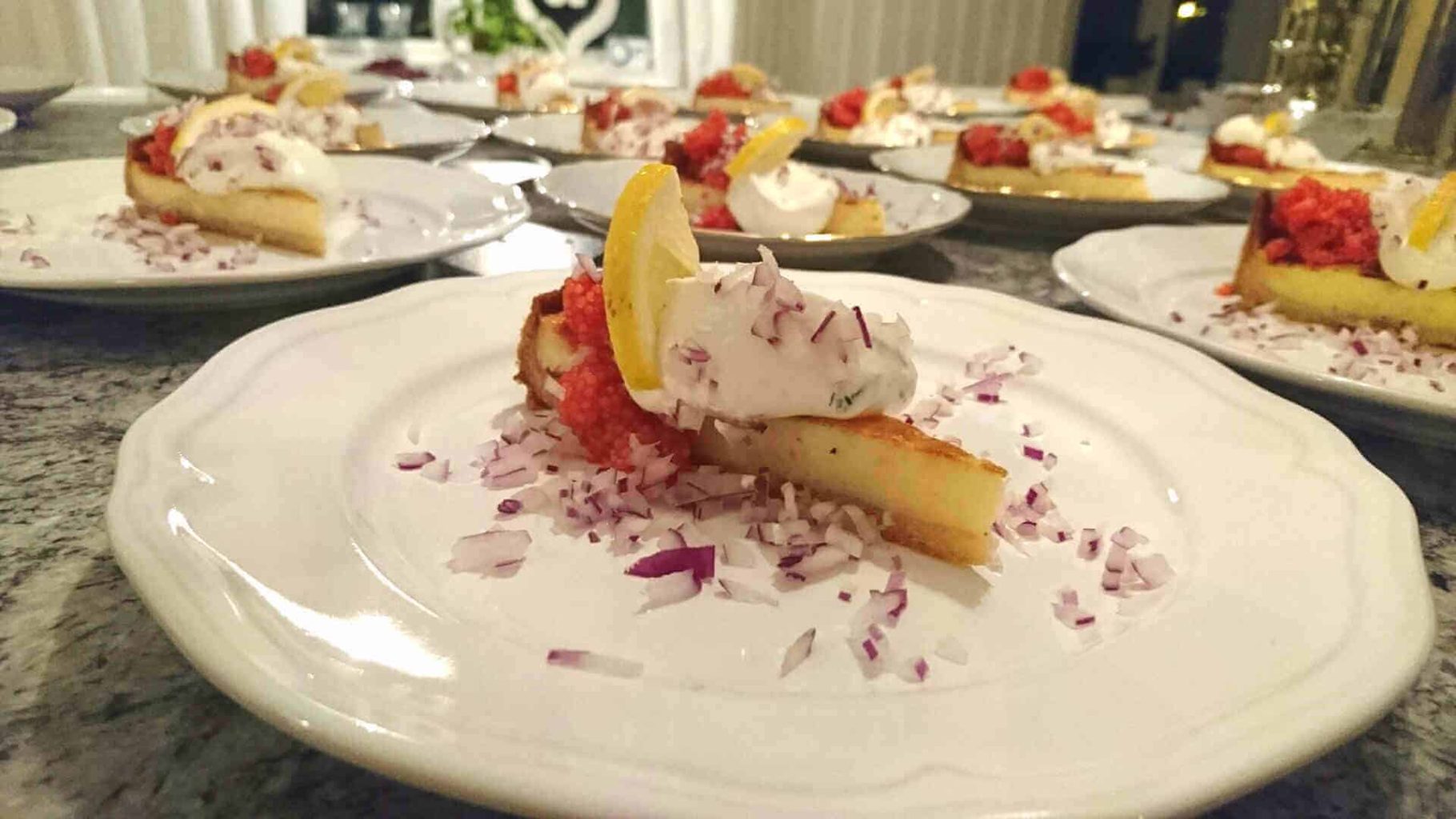 Svamppaj 8 Västerbottensostpaj serverad med lök, gräddfil och citron på en tallrik.