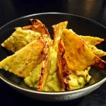 En skål med zucchinichips som är placerade runt guacamole.