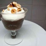Skål med chokladmousse toppad med vispad grädde och hackade nötter.