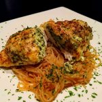 Hasselbackkyckling fylld med fetaost serverad på en tallrik med pasta.