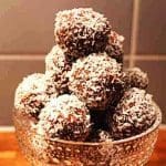En skål med chokladbollar rullade i kokosflingor, staplade ovanpå varandra.