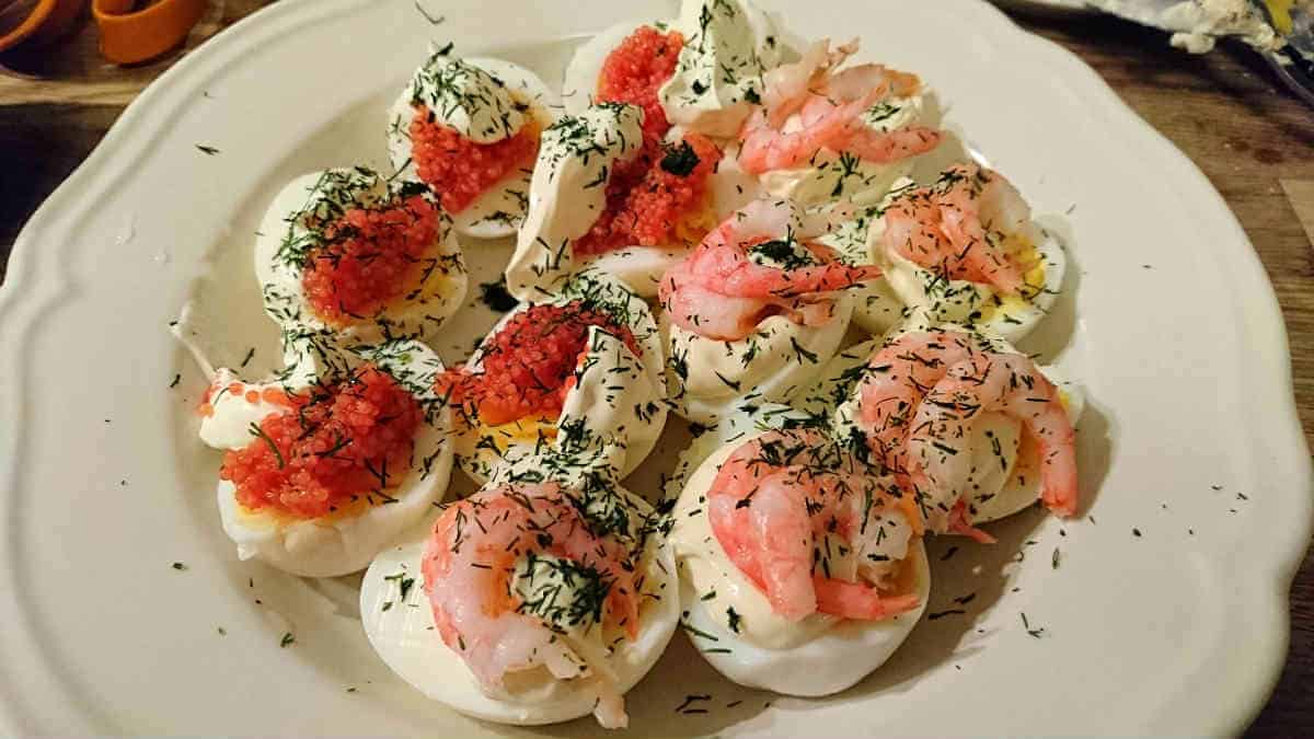 Ägghalvor med avokado och chili 9 Ägghalvor toppade med räkor, röd kaviar och dill på en tallrik.