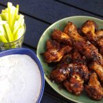 En tallrik med buffalo wings, en skål med dipp och en glasburk med selleristavar.
