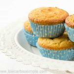 Flera mejerifria muffins i blåa pappersformar med vita prickar på en vit tallrik.