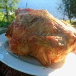 Grillad kyckling placerad på en vit tallrik med grön bakgrund.