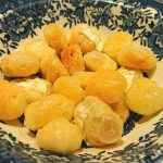 En skål med briepuffar som är gyllene och krispiga, placerade på en blå och vit mönstrad tallrik.