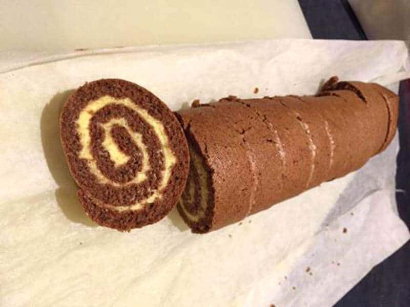 Sockerfri kladdkaka 5 Chokladrulltårta skuren i skivor med vaniljfyllning synlig i mitten.