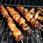 Tre grillade kycklingspett med svamp på ett grillgaller.