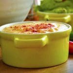 Kryddig cheddar dipp i en gul skål med paprika på toppen, med en annan grön skål i bakgrunden.