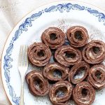 En tallrik med chokladrulltårta skuren i skivor, med vaniljfyllning synlig i mitten.