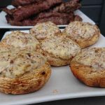 Grillade champinjoner fyllda med ost på en vit tallrik.