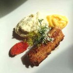 En tallrik med stekt torskrygg, saffransaioli, potatismos och dekorationer av grönsaker.
