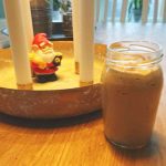 Ett glas med kall dryck placerat på ett bord bredvid en julfigur i en skål.