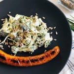 En tallrik med grillad korv och en broccolisallad med solrosfrön.