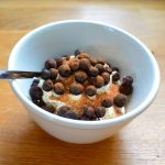 Skål med gräddig dessert toppad med blåbär och kanel i en vit skål.