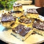 Kokosrutor med chokladöverdrag och kokosflingor på en tallrik.
