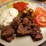 En tallrik med köttfärs, grönsaker, sås och salsa på en vit tallrik.