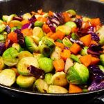 En blandning av stekta brysselkål, rödkål och morötter i en stekpanna.