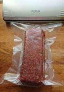 Vakuumförpackad köttfärs i en plastpåse på en träyta.