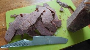 Skivor av köttfärs på en grön skärbräda med en kniv bredvid.