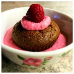 Chokladmuffin toppad med hallonsås och ett hallon i en skål.