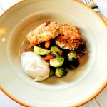 Två kycklingfärsbiffar serverade med grönsaker och en klick sås i en skål.