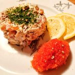 Lax tartar serverad med citronskivor och röd rom på en tallrik.