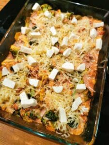 En gratäng med broccoli, ost och bitar av fetaost i en ugnsform.