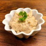 En liten skål med baconnaise, en krämig sås, dekorerad med en grön ört.