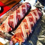 Två baconlindade köttfärslimpor på en plåt med aluminiumfolie.