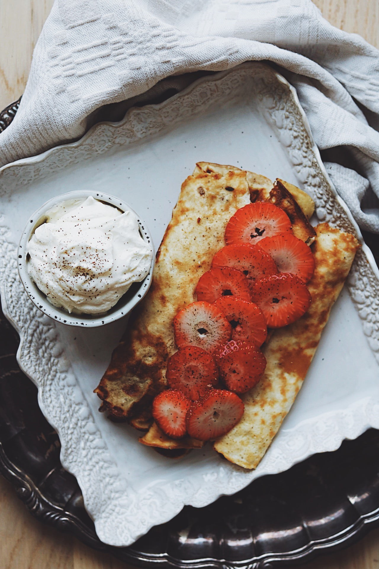 Enklaste pannkakorna 4 Pannkakor på en tallrik med jordgubbar och grädde i en skål bredvid.