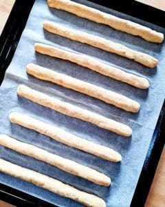 Raka degstänger placerade på en bakplåt med bakpapper.