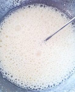 En skål med skummig jäst deg som har en ljus färg och bubblor på ytan.