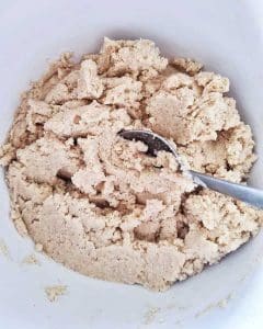 En skål med en blandning av mandelmjöl och vatten, med en sked som ligger i blandningen.